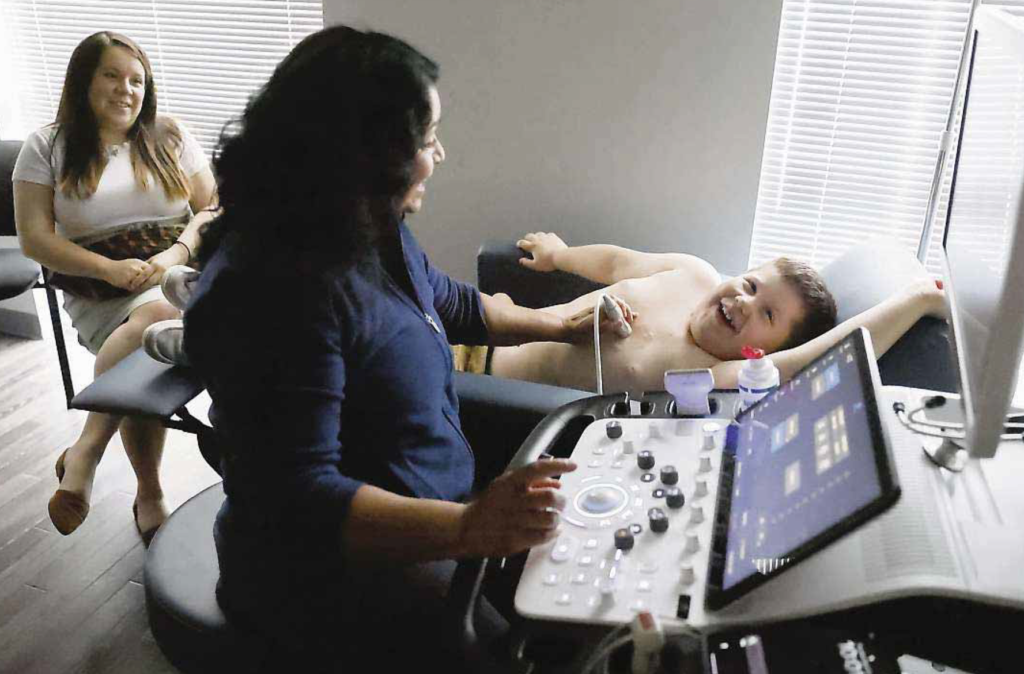 therapist, pediatric patient and caregiver with medical equipment